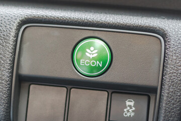 Green ECON button in car dashboard, economy switch for power saving, economical energy driving technology in EV electric vehicle and hybrid engine automobile system