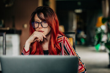 Redhead European Woman is Surfing Internet for a job in IT on laptop computer at home