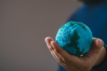 A person holds a small globe, symbolizing care for the Earth and environmental awareness.