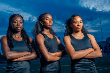 Three athletes pose against a dramatic cloudy sky backdrop. USA