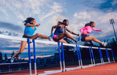 Three athletes in vibrant sportswear jumping hurdles on a track with a scenic sky backdrop. USA