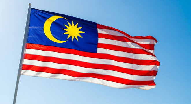 Dynamic Malaysian flag waving proudly against a bright blue sky, a symbol of national pride