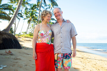 A smiling couple stands on a sunny tropical beach with palm trees and ocean in the background. Kepaniwai Park, Wailuku, Hawaii