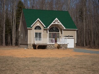 Obraz premium A small house with a green roof sits in a grassy yard. The house is surrounded by trees and has a porch