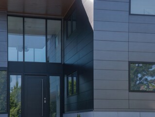 A large house with a black front door and a large window. The house is made of metal and has a modern design