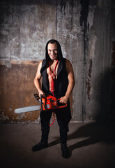 Sinister man with a chainsaw grins menacingly in a grunge abandoned room