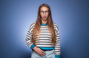 Impressed young woman looking at camera and say what, isolated on blue background.