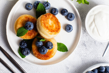 syrniki . Appetizing cheesecakes with sauce and blueberries