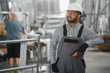 Operator of machine. Industrial worker indoors in factory. Young technician in white hard hat