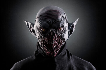 Portrait of a monster with sharp fangs over dark foggy background.