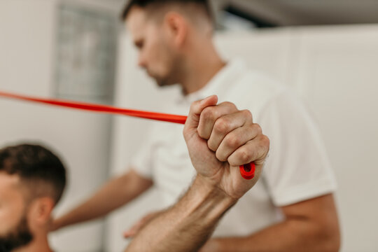 Physiotherapist assisting patient doing exercises with resistance band