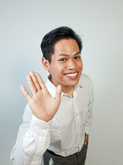 Smiling Man Waving in a Formal White Shirt with Friendly Gesture. Person displaying a welcoming...
