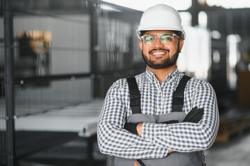 Smiling and happy indian employee. Industrial worker indoors in factory. Young technician with...