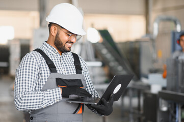 Young Indian male engineer wearing safety workwear standing in the factory