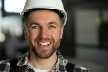 Smiling and happy employee. Portrait of industrial worker indoors in factory. Young technician with...