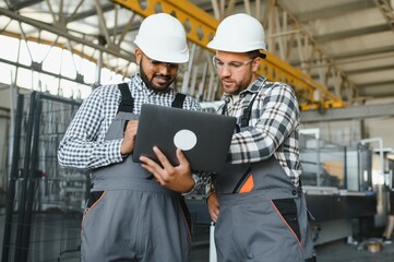 Two workers at a factory for the production of metal plastic windows and doors.