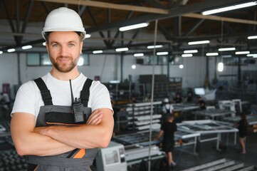 Smiling and happy employee. Portrait of industrial worker indoors in factory. Young technician with...