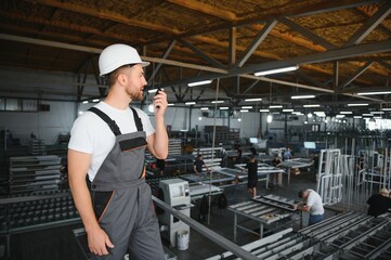 Men industrial engineer wearing a white helmet while standing in a heavy industrial factory behind