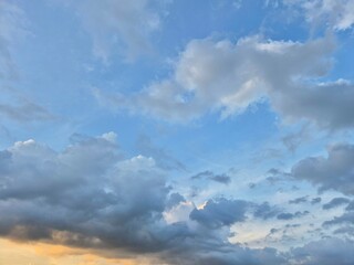 Sunset sky with fluffy white and gray clouds forming soft patterns overhead