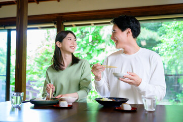 和風の家で並んで食事をする日本人男女