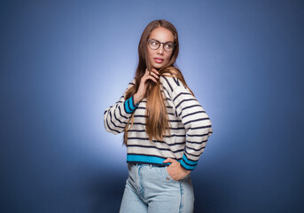 Beautiful woman posing, isolated on blue background. Pretty girl looking to side. Copy space.