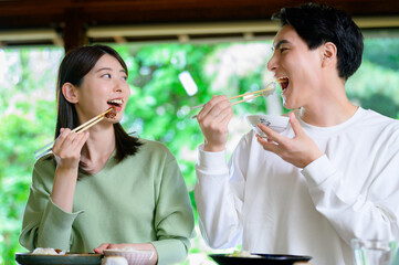 和風の家で並んで食事をする日本人男女