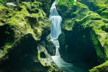 waterfall behind rock slow shutter photo tropical river green moss humid rock stone rapids