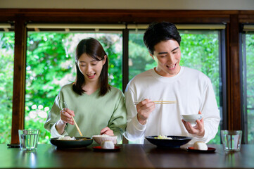 和風の家で並んで食事をする日本人男女