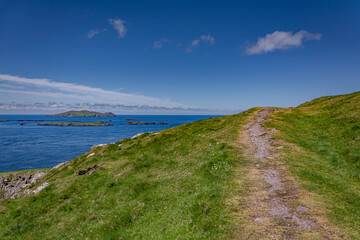 footpath on the hill with a view of the coast of the atlantic ocean at dingle peninsula