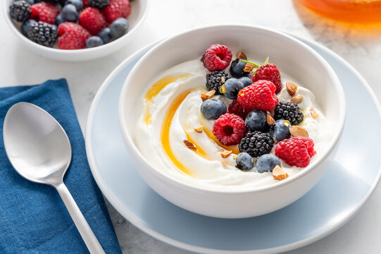 Greek yogurt bowl with raspberries, blueberries, blackberries, almonds and honey for breakfast. Healthy tasty snack. Selective focus