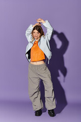 Young beautiful woman in summer attire expressing joy against a vibrant purple background