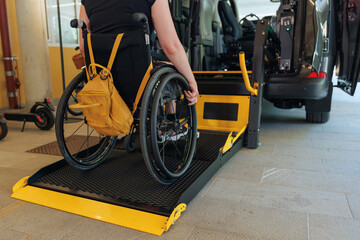 Woman with disability accesses a vehicle using a lift in a parking area, showcasing mobility...