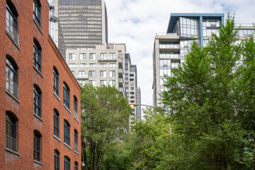 Mix of modern glass and concrete buildings, along with an older red brick building, suggests a...