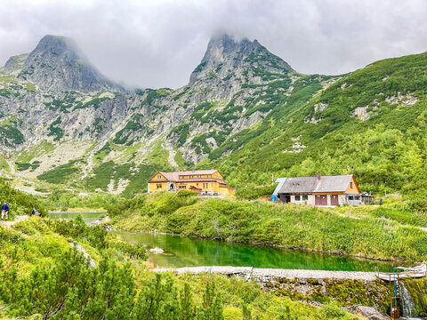 Lonely house on the High Tatras peaks (Chata pri zelenom plese), lush greenery valley, mountain lake. Zelene Pleso (Green lake) mountain lake in High Tatras, Slovakia
