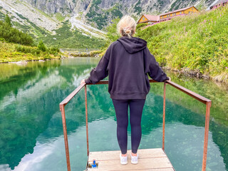 Young woman standing and admiring the High Tatras peaks and mountains view. Hiking trail in High...