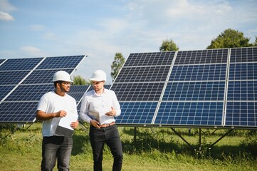 The solar farm, solar panel with two engineers walk to check the operation of the system,...