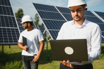 Two engineers or businessmen on the background of solar panels. Renewable energy. Green energy