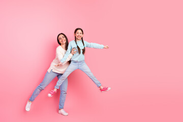 Mother and daughter enjoying a cheerful bonding moment together against a vibrant pink background embracing youthful joy