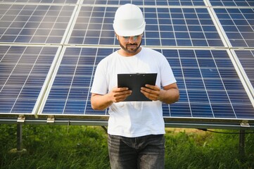 Portrait of a young Indian male engineer working in a field of solar panels