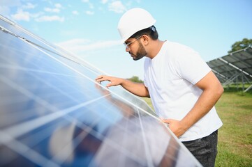 Portrait of Young indian male engineer standing near solar panels, with clear blue sky background, Renewable and clean energy. skill india, copy space