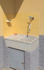 Water tap with stone sink on terrace in courtyard of house in summer, Italy. Buildings and...