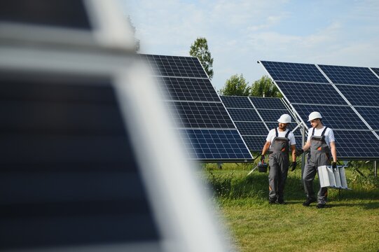 A team of two engineers are working to install solar panels at a solar power station. Engineer team discussing the work to install solar cells