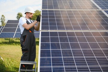 Man technician mounting photovoltaic solar moduls. Engineer in helmet installing solar panel system...