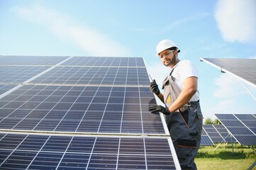 Portrait of an Indian worker talking on a walkie talkie against the background of solar panels