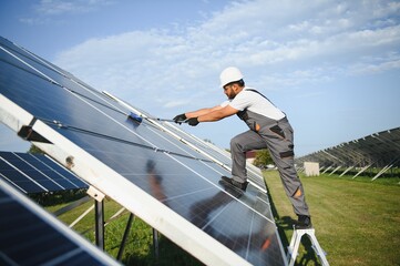 A young Indian cleaning service worker cleans solar panels
