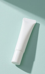 White cosmetic cream tube mockup on a light blue background with a hard shadow from sunlight. Minimalist beauty product concept.