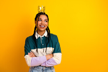 Cheerful young woman with braided hair wearing a colorful outfit and gold crown in front of a...