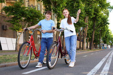 Obraz premium Teenage girl and boy with bicycles on city street
