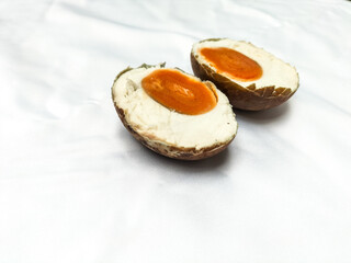 A photo of grilled salted egg on white background. Grilled salted egg is cut in half. Food culinary from indonesia, black color smoked salted egg.
