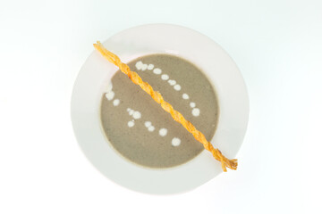 Smooth creamy mushroom soup paired with bread sticks on white background
